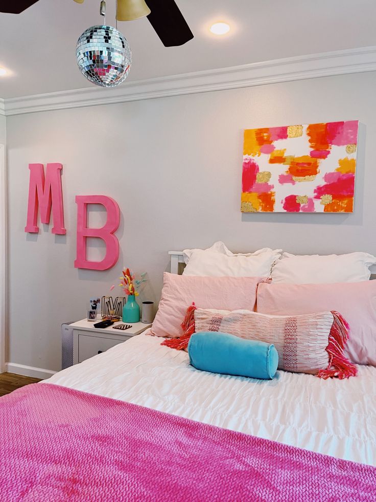 a bed with pink sheets and pillows in a bedroom