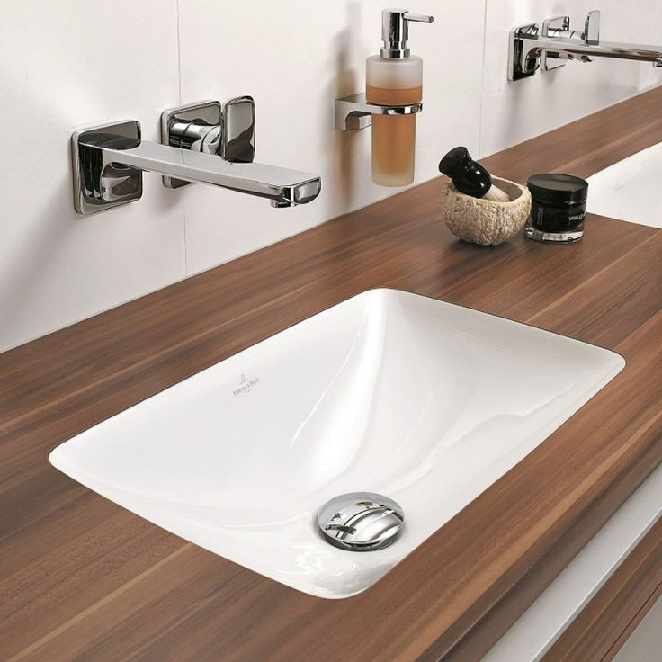 a bathroom sink with soap dispensers on the wall above it and wood countertop