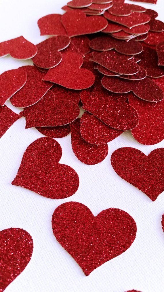 red glitter heart confetti on white background