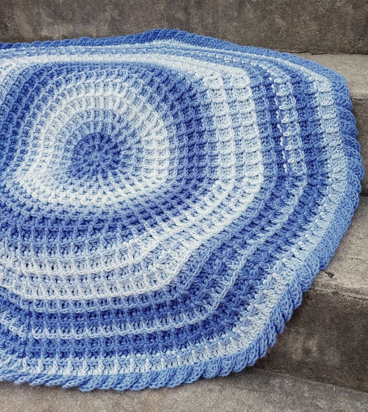 a blue and white crocheted rug sitting on the steps