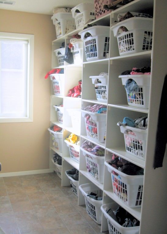 the closet is filled with lots of white baskets and clothes on shelves next to a window