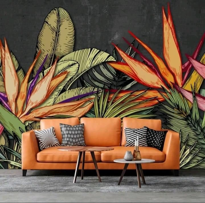 an orange couch sitting in front of a wall with tropical leaves on it's side