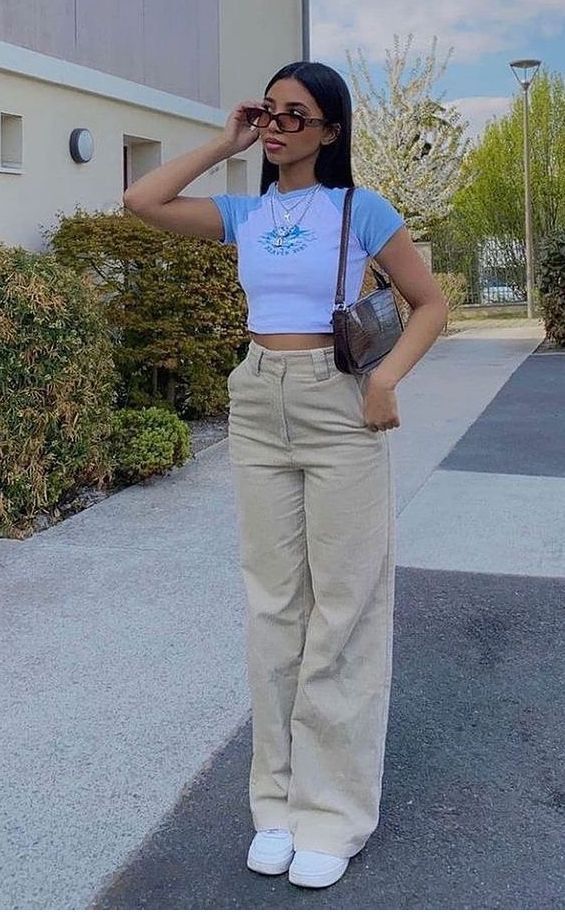 a woman standing in front of a building with her hand on her hip and looking off to the side