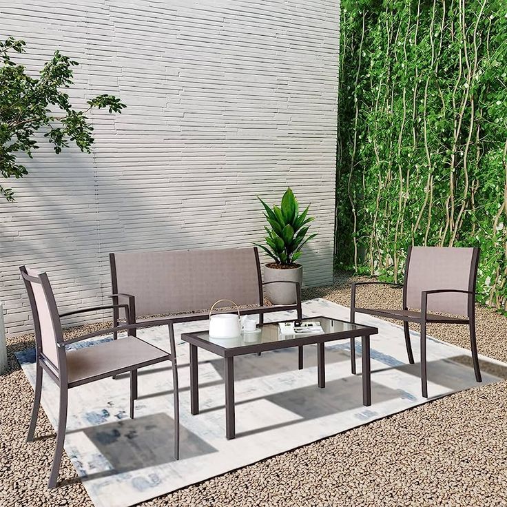 a table and chairs sitting on top of a gravel covered ground next to a wall