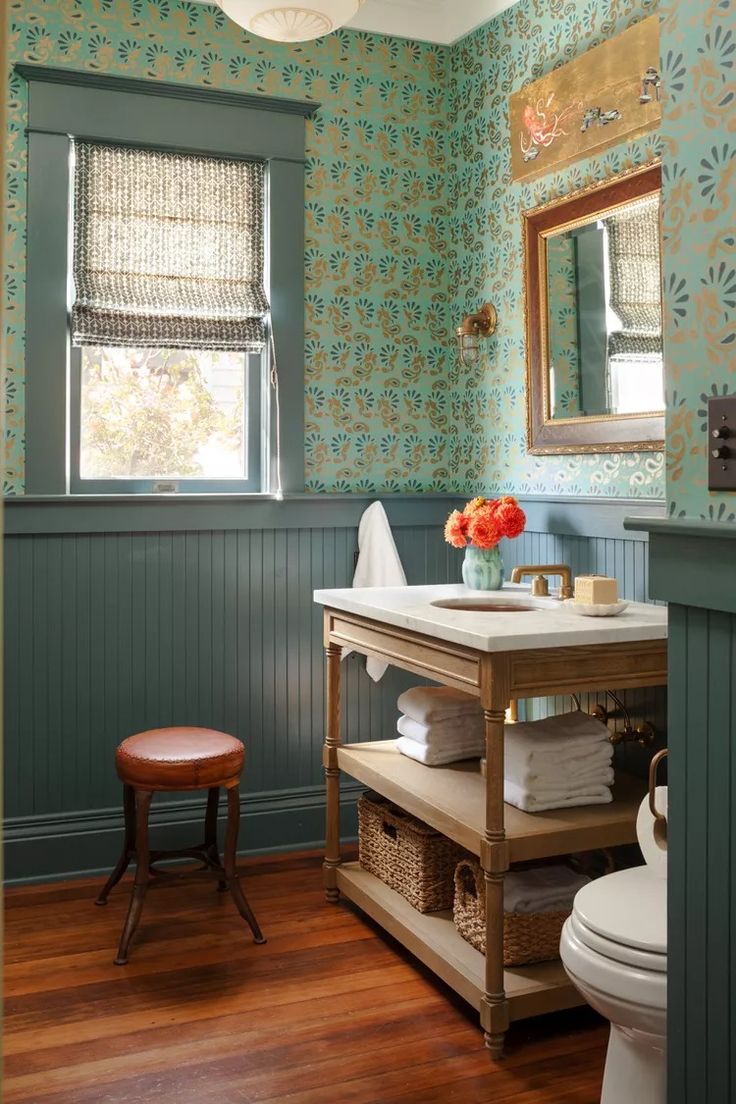 a bathroom with blue walls and wood floors, including a vanity table in the center