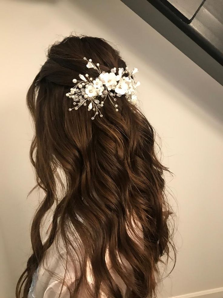 the back of a woman's head with long hair and flowers in her hair