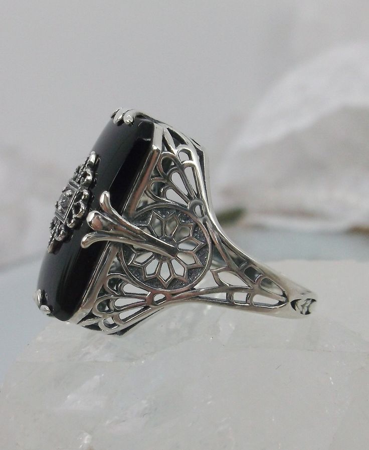 Black Glass/Stone & CZ Ring Grace Design#233 Custom Made I now offer this lovely Antique Art Deco/Edwardian design ring in sterling silver. This gorgeous ring is set with a stunning floral filigree embellished black glass/resin with a centered set 1mm white CZ. The Black glass is 18mm Long by 19mm Wide. The ring sits 19mm NS in the finger and 10mm EW on the finger. The inside of the band is marked 925 for sterling. Notice the beautiful leaf geometric design of the filigree band and setting. Black Filigree Ring With Intricate Design For Formal Occasions, Black Filigree Ring For Formal Occasions, Classic Black Filigree Ring For Formal Occasions, Antique Black Jewelry For Wedding, Black Jewelry With Intricate Design For Anniversary, Elegant Black Filigree Ring For Anniversary, Antique Black Wedding Jewelry, Black Intricate Jewelry For Anniversary, Formal Black Filigree Ring