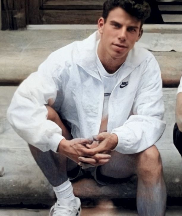 two tennis players sitting on the steps in front of some stairs and one is holding his hands together