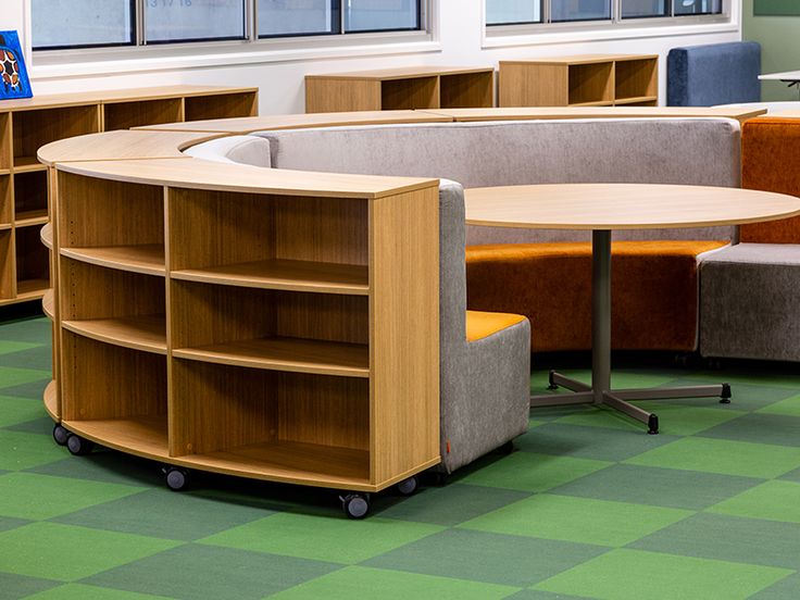 an office with circular tables and chairs in it's cubicle, which also has bookshelves