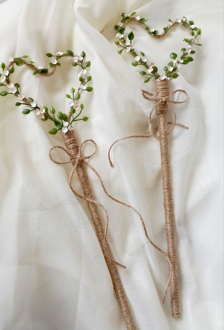 two branches with flowers tied to them are laying on a white cloth covered bed sheet