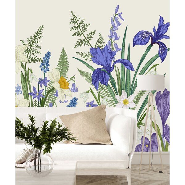 a white couch sitting next to a wall with blue flowers and plants painted on it