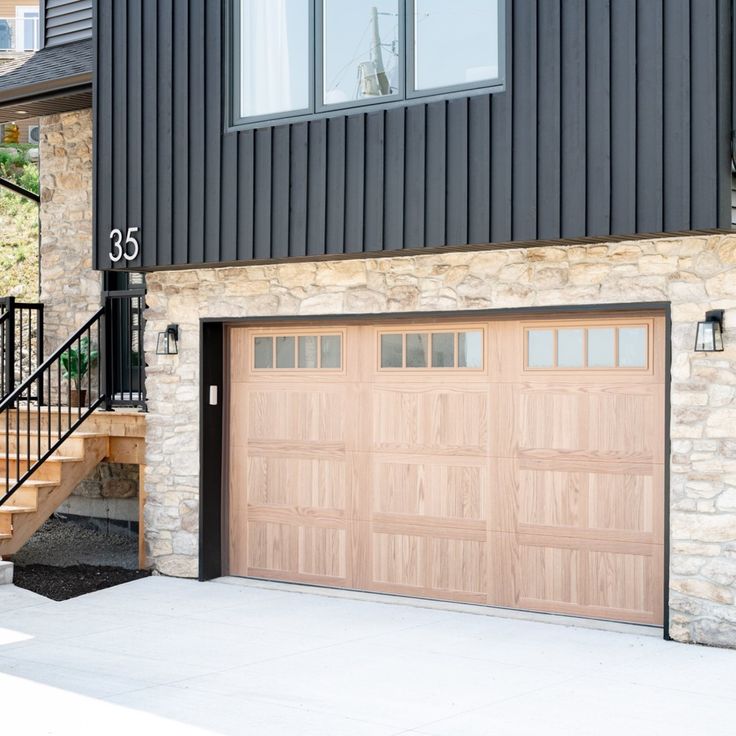 two garage doors are open in front of a stone building with stairs leading up to it