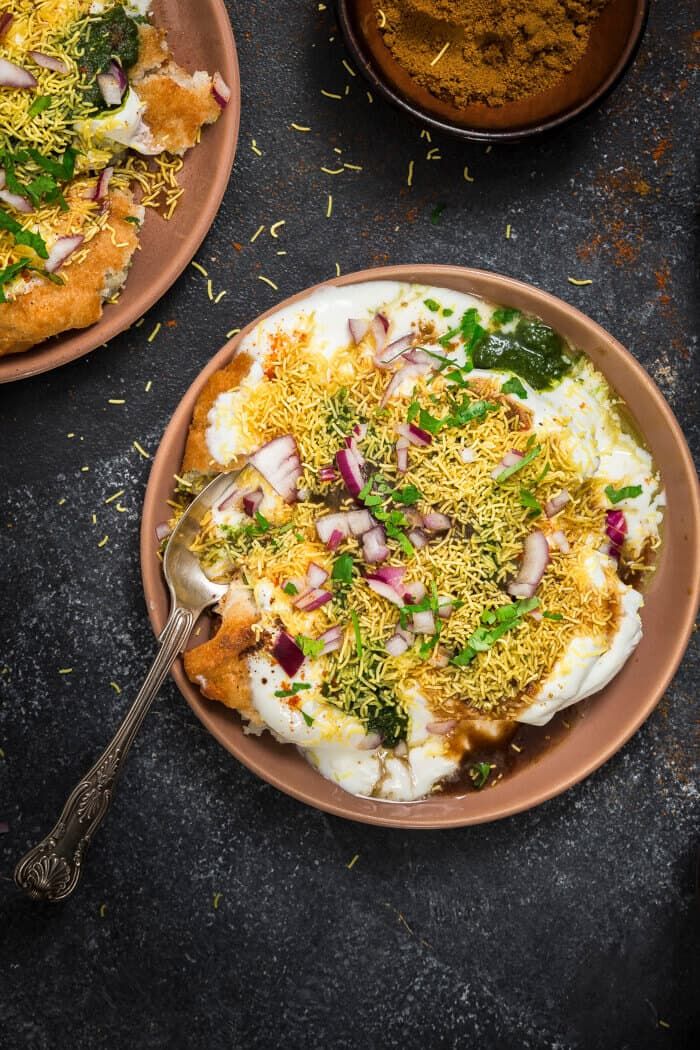 two plates filled with food on top of a black table next to bowls of spices and seasonings