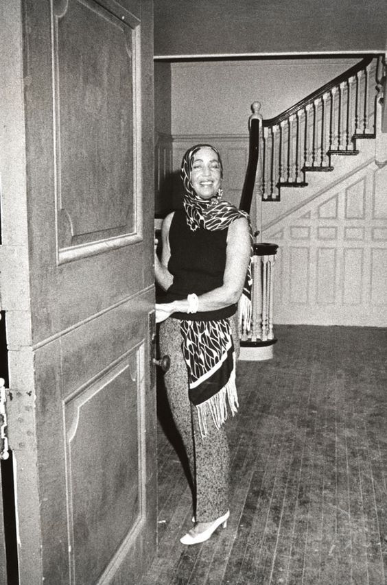 a woman standing in an open doorway with her hand up