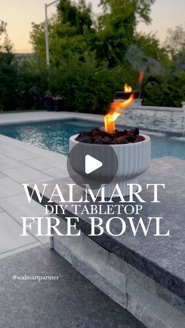 a fire bowl sitting on the edge of a pool