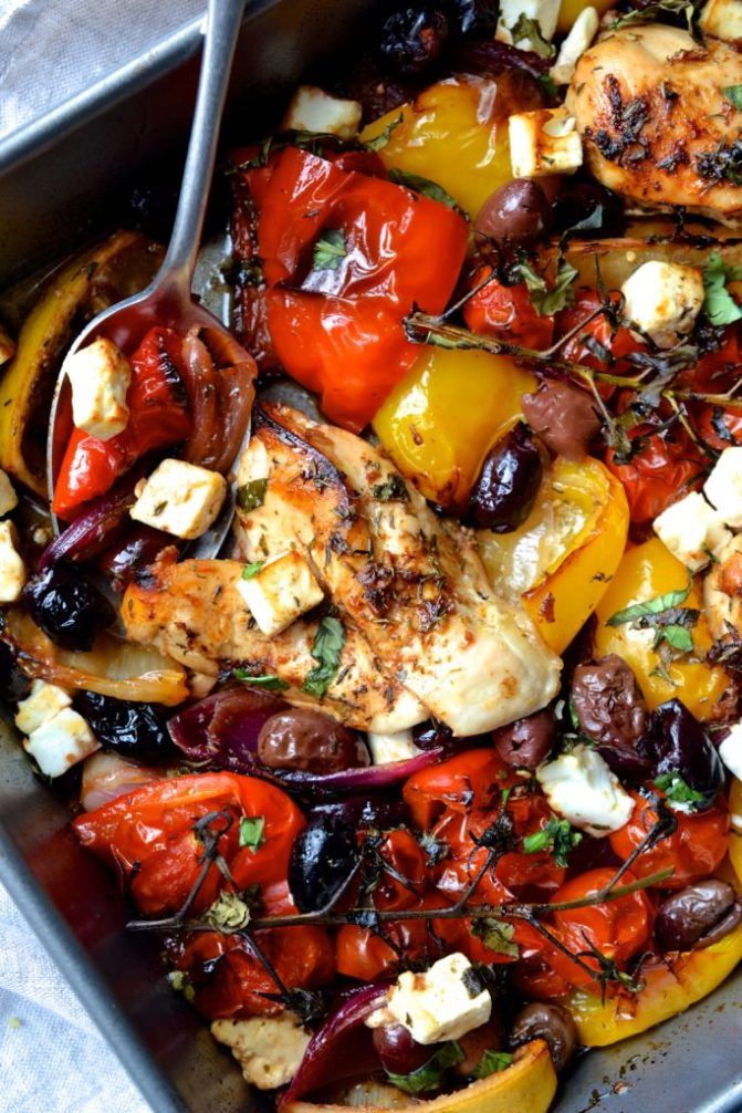 a pan filled with chicken and vegetables on top of a table next to a fork