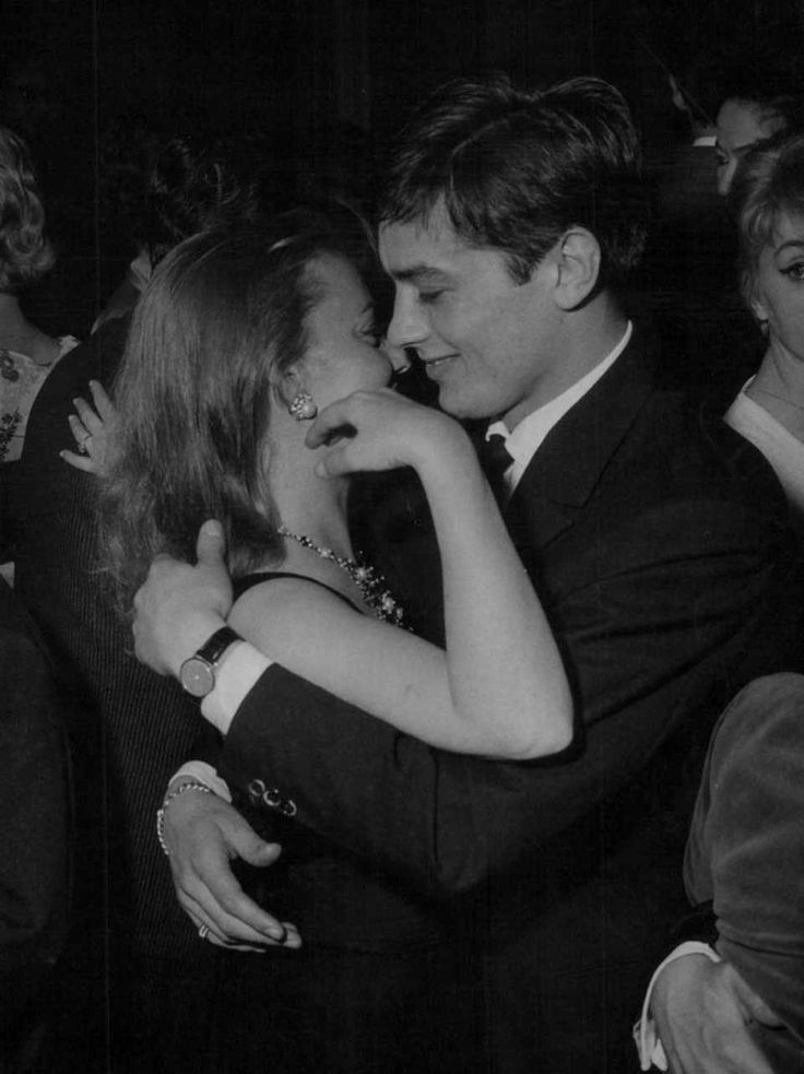 a man and woman hugging each other at an event in black and white, with people looking on