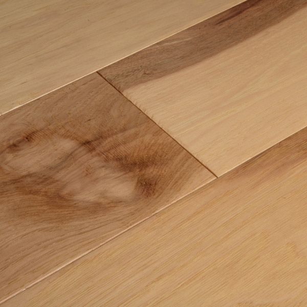 a close up of a wooden floor with a knife on it's end and a piece of wood in the background