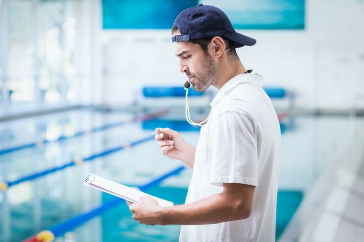 a man wearing ear buds and listening to music while standing in front of a swimming pool