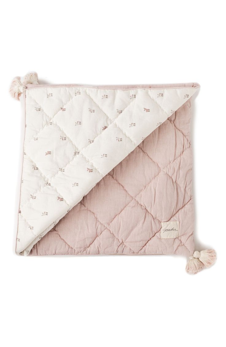 a pink and white blanket with tassels on the bottom, folded over it