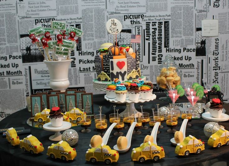 a table topped with cakes and desserts covered in yellow frosting on top of a black table cloth