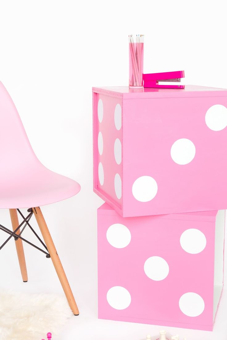 a pink desk with white polka dots on it and a plastic chair next to it