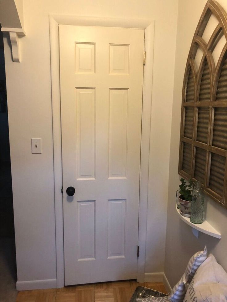 a white door in a room with wood flooring and pillows on the floor next to it