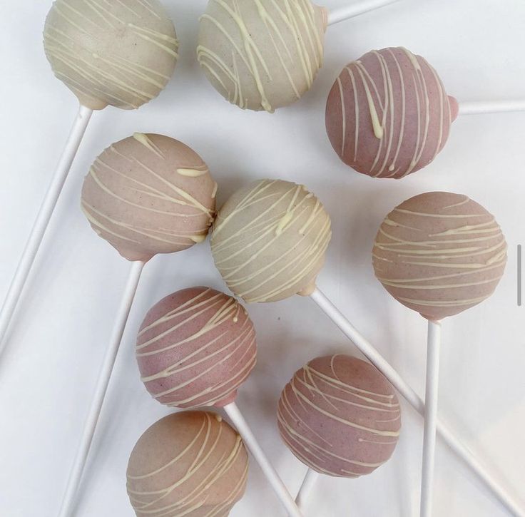 several lollipops are lined up on top of each other with white and pink icing