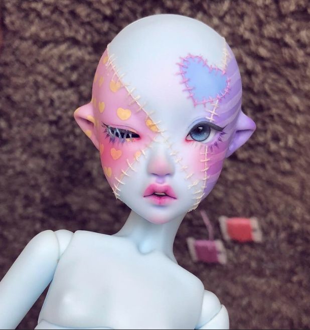 a close up of a doll with pink and blue paint on it's face