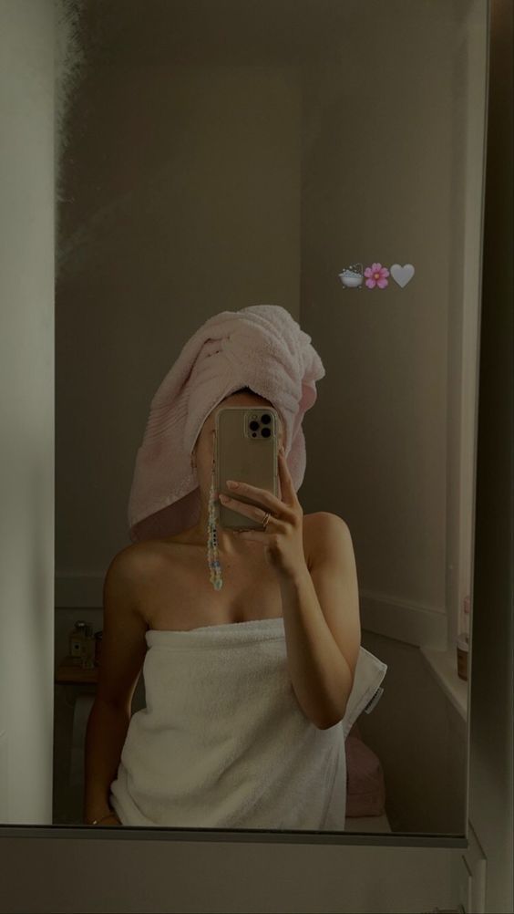 a woman with a towel on her head taking a selfie in the bathroom mirror