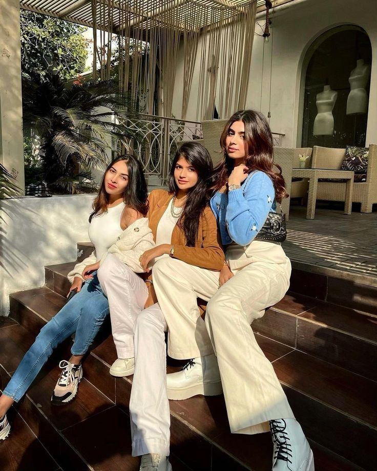 three women sitting on steps in front of a house