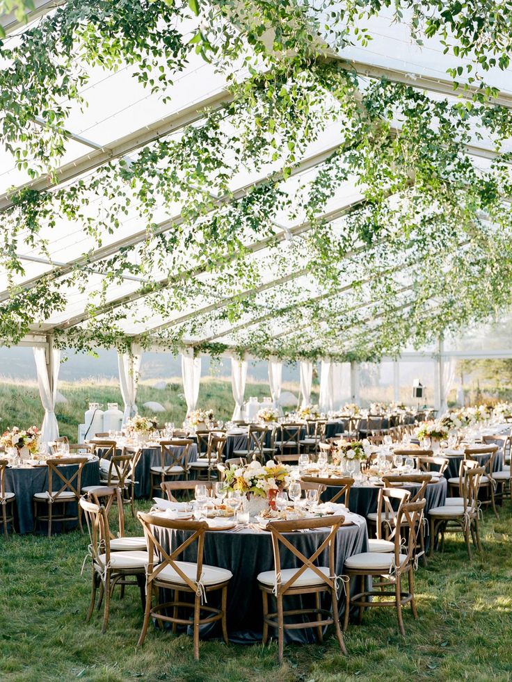 an outdoor tent with tables and chairs set up for a wedding reception under the canopy