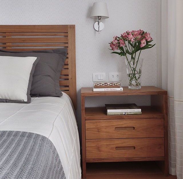 a bedroom with a bed, nightstand and flowers on the night stand next to it