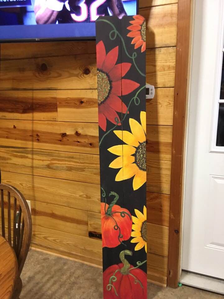 a skateboard with sunflowers and pumpkins on it in front of a tv