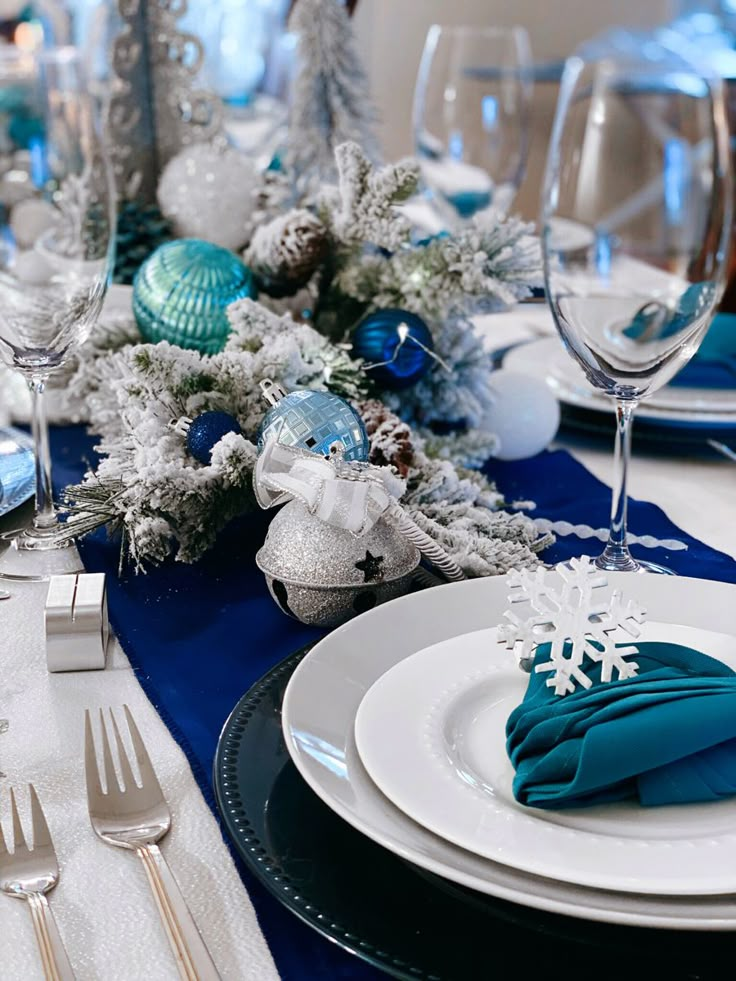 the table is set for christmas dinner with silverware and blue napkins on it