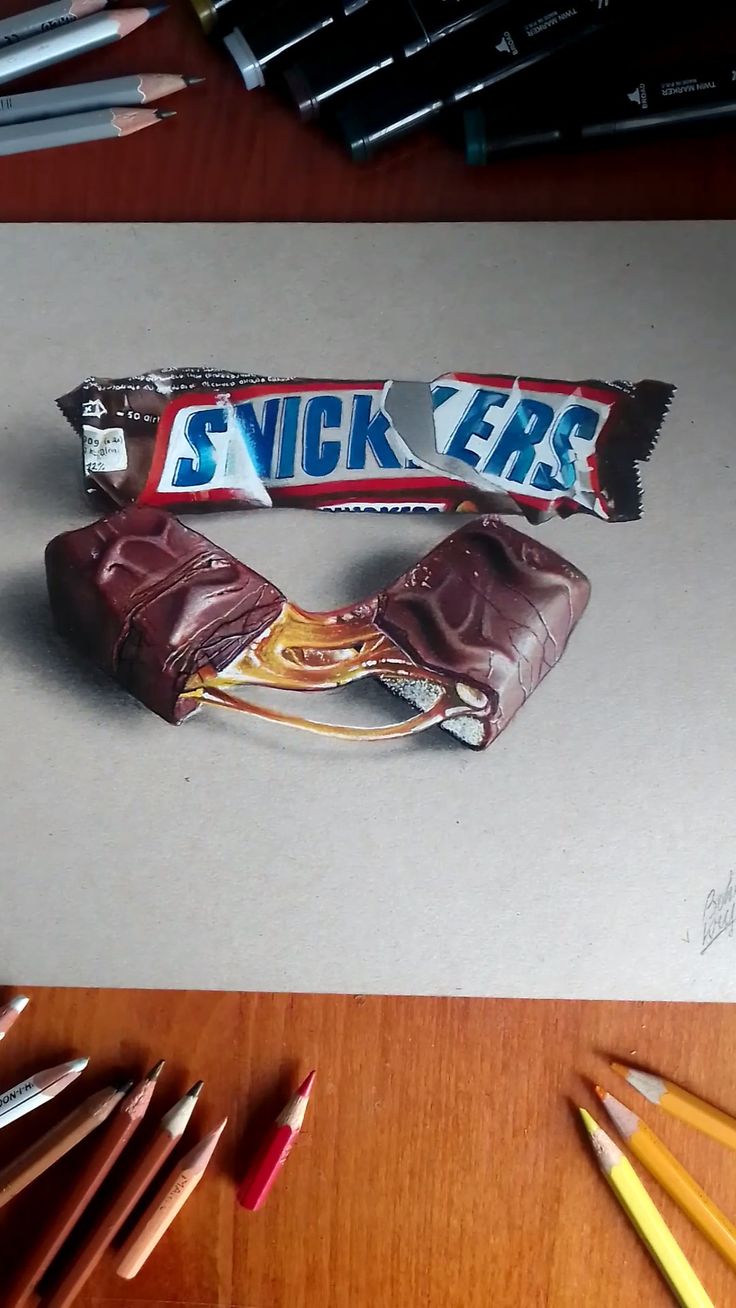 some pencils are laying on a table next to an art project with candy bars