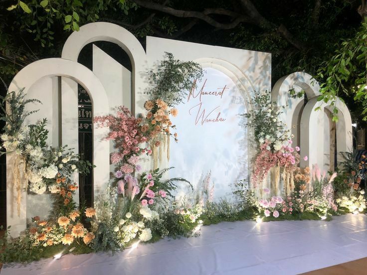 a decorated stage with flowers and greenery on the side for a wedding ceremony or reception