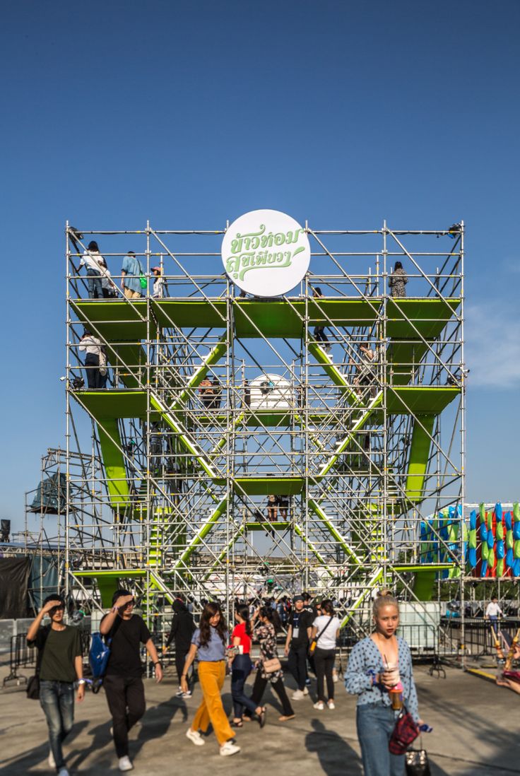 people are walking around in front of a large structure that has a sign on it