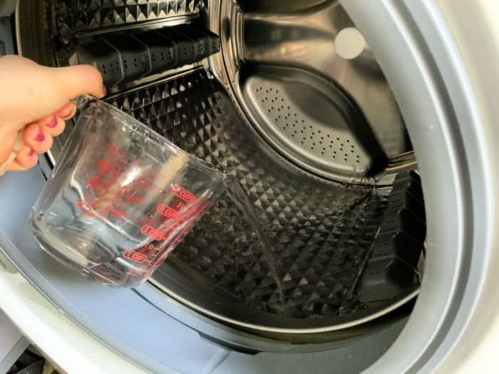 someone is holding a cup in front of the washing machine