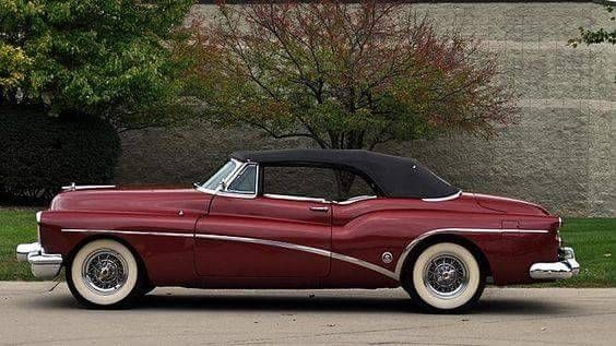 an old fashioned red car parked on the street