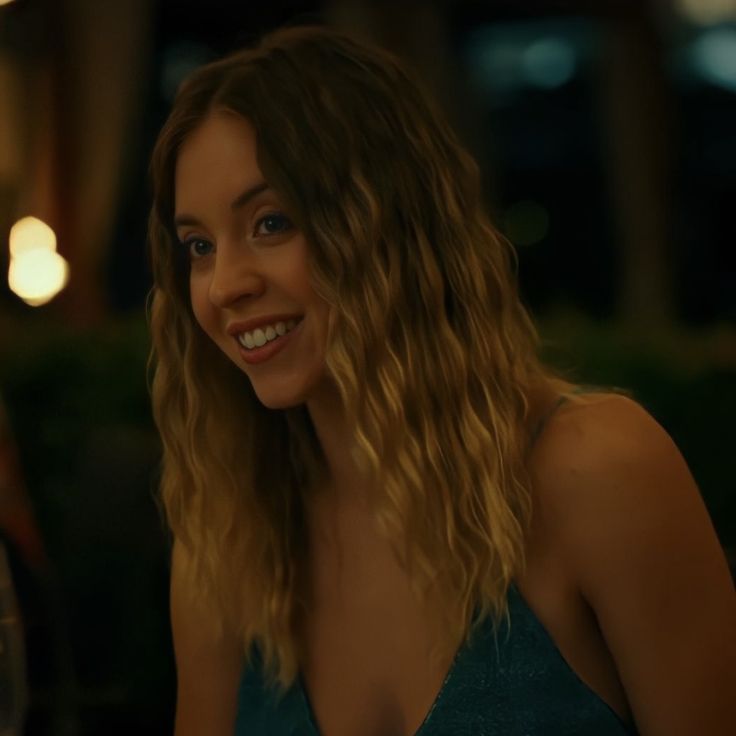 a woman sitting at a table with a glass of wine in her hand and smiling