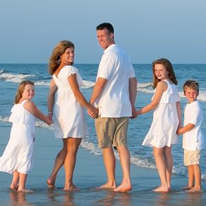 a family standing on the beach holding hands