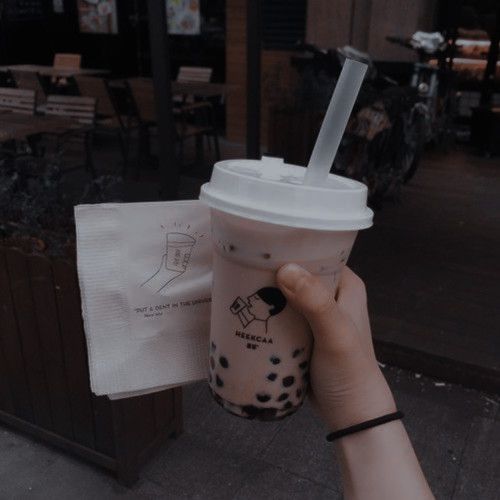 a person holding up a cup with a straw in it