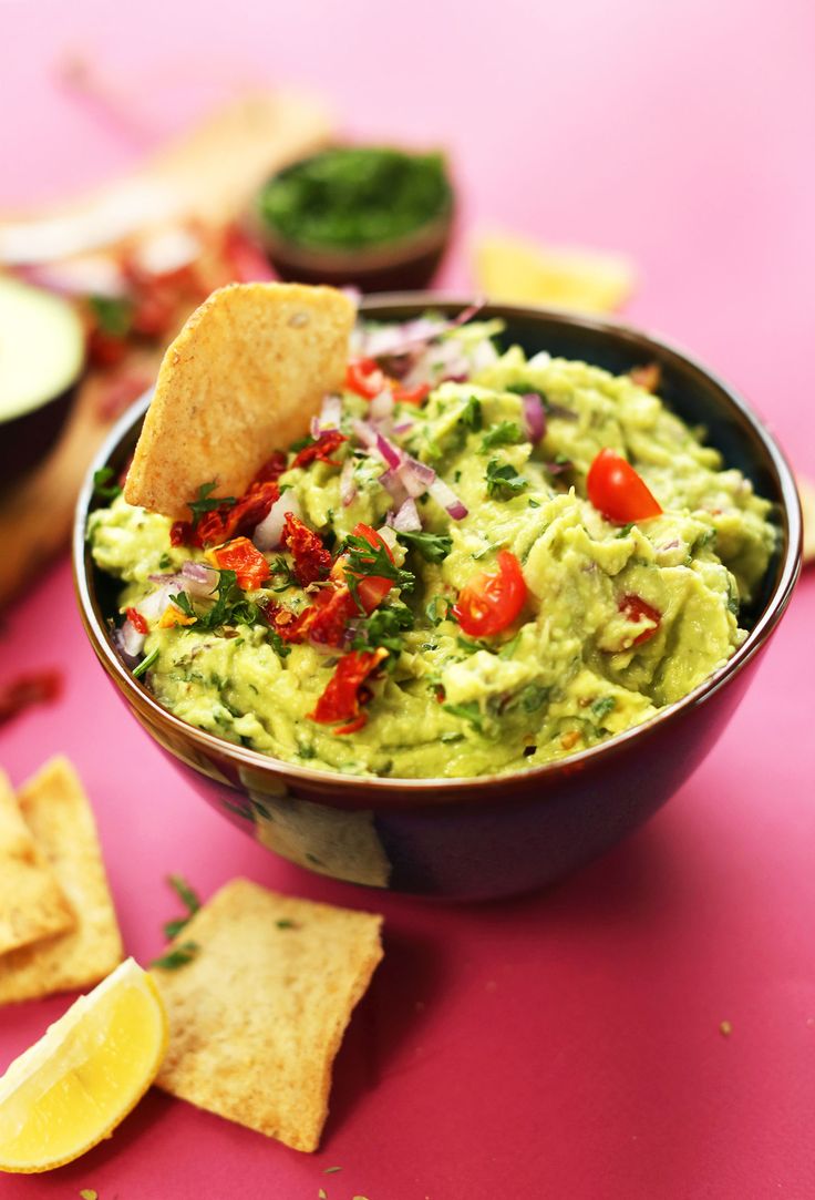 a bowl filled with guacamole surrounded by tortilla chips and salsa