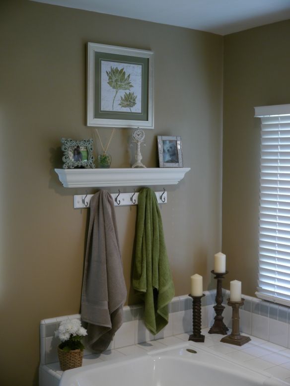 a white sink sitting under a window next to a towel rack with candles on it