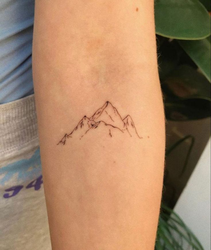 a small mountain tattoo on the arm