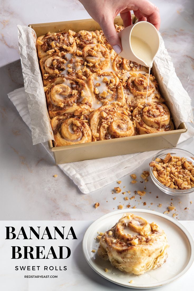 a person pouring syrup on top of a box of cinnamon buns next to a plate of food