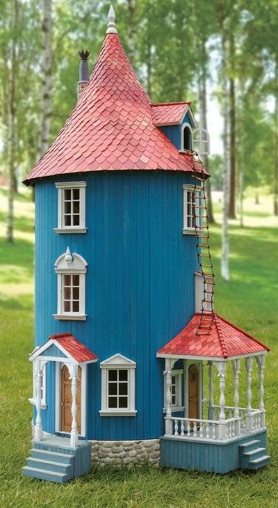 a blue doll house sitting on top of a lush green field