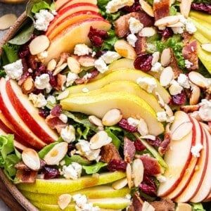 an apple salad with nuts and cranberries in a wooden bowl on a table