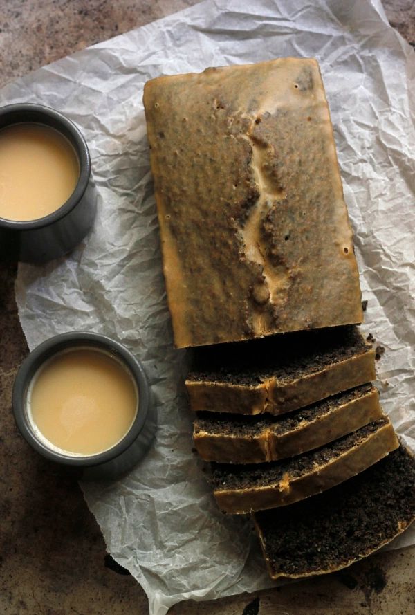 sliced loaf of bread sitting on top of a piece of wax paper next to two cups of coffee